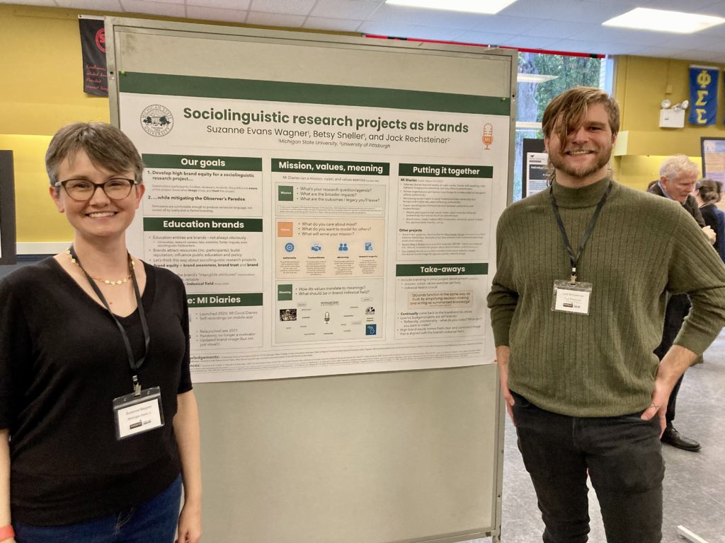 Suzanne Wagner and Jack Rechsteiner stand in front of the Wagner, Sneller & Rechsteiner poster at NWAV 51.